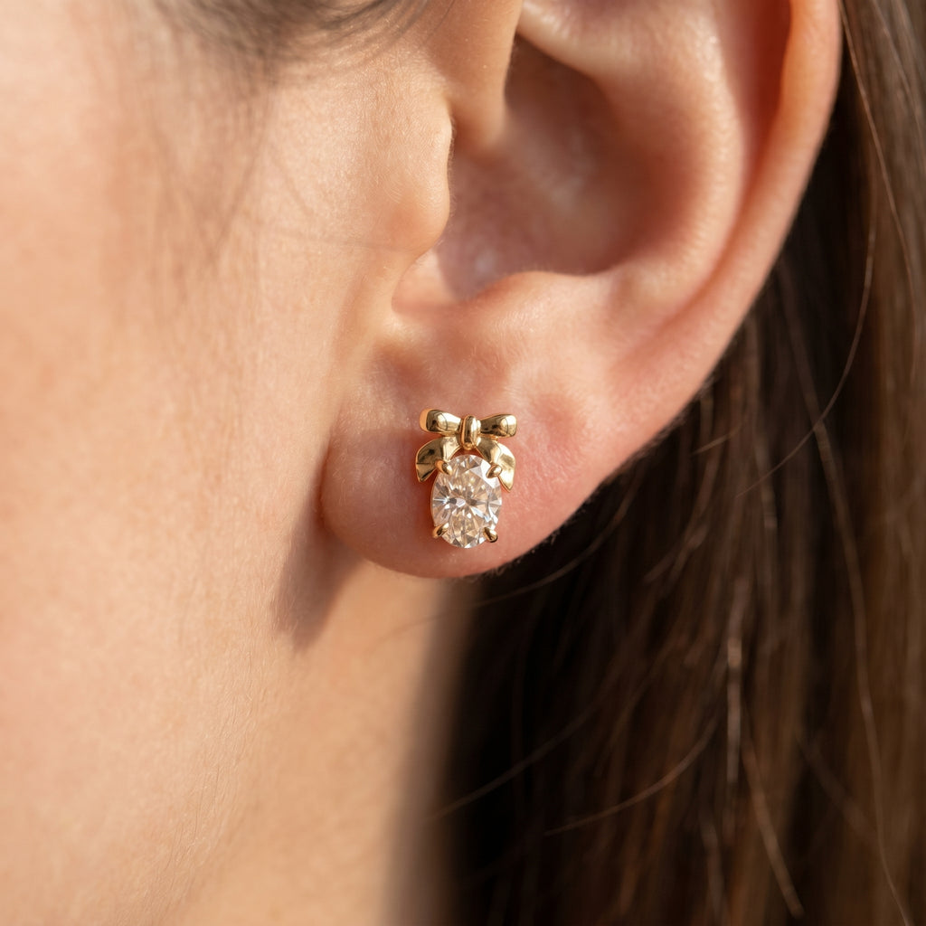 Side profile of oval diamond bow earrings showing secure prong setting and polished luxury metal craftsmanship