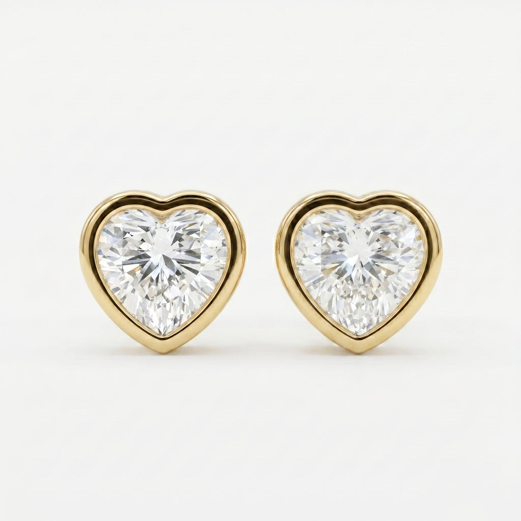 Heart-shaped diamond earrings with gold settings on a white background