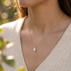 Gold necklace with a pendant worn by a person outdoors