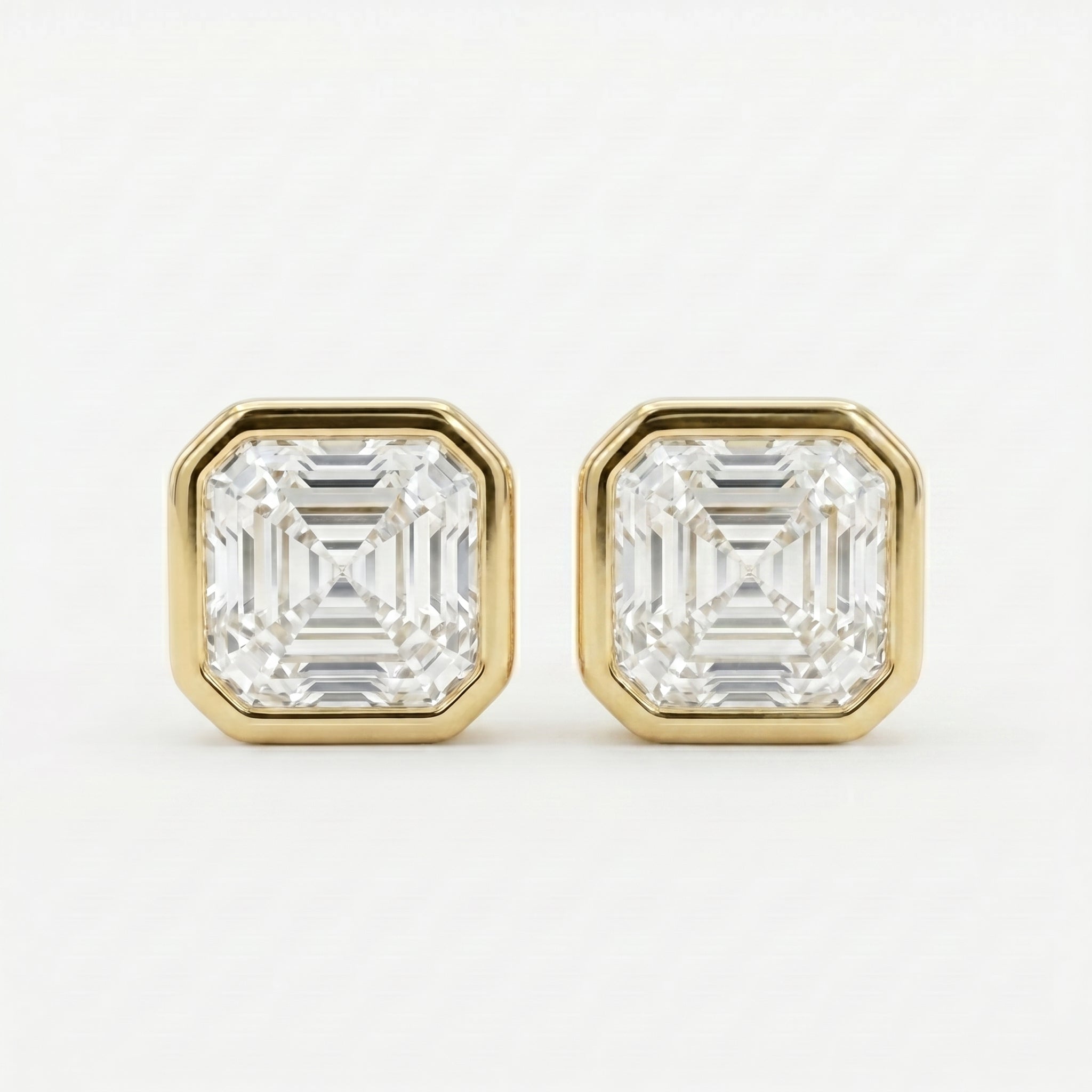 Gold earrings with Ascher-cut gemstones on a white background