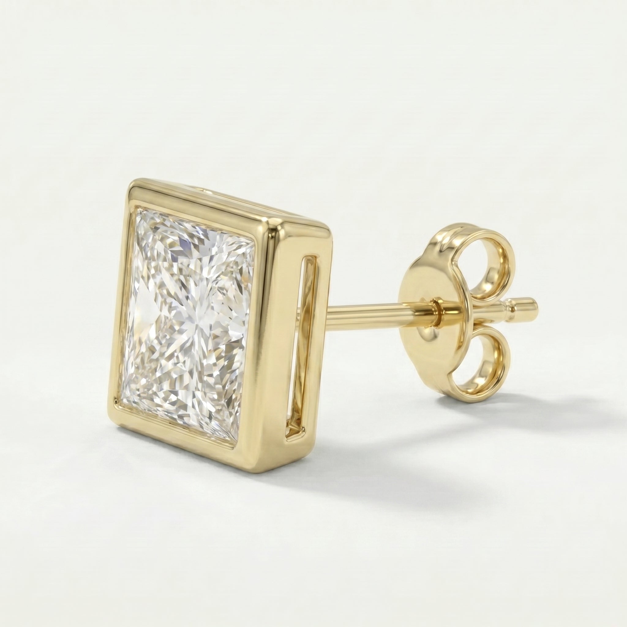 Gold earring with a clear gemstone on a light gray background
