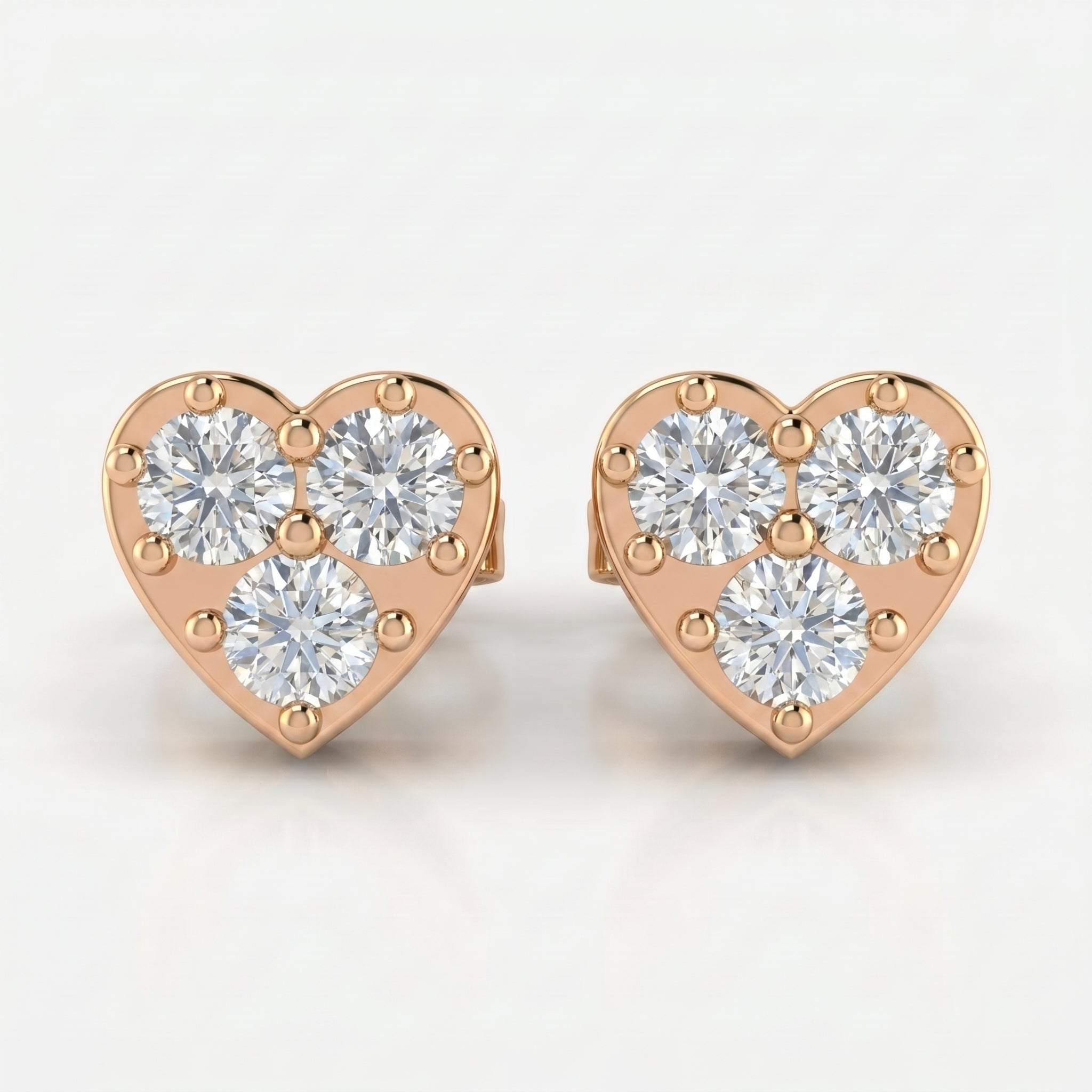 Rose gold heart diamond stud earrings with three round brilliant stones on a clean white background