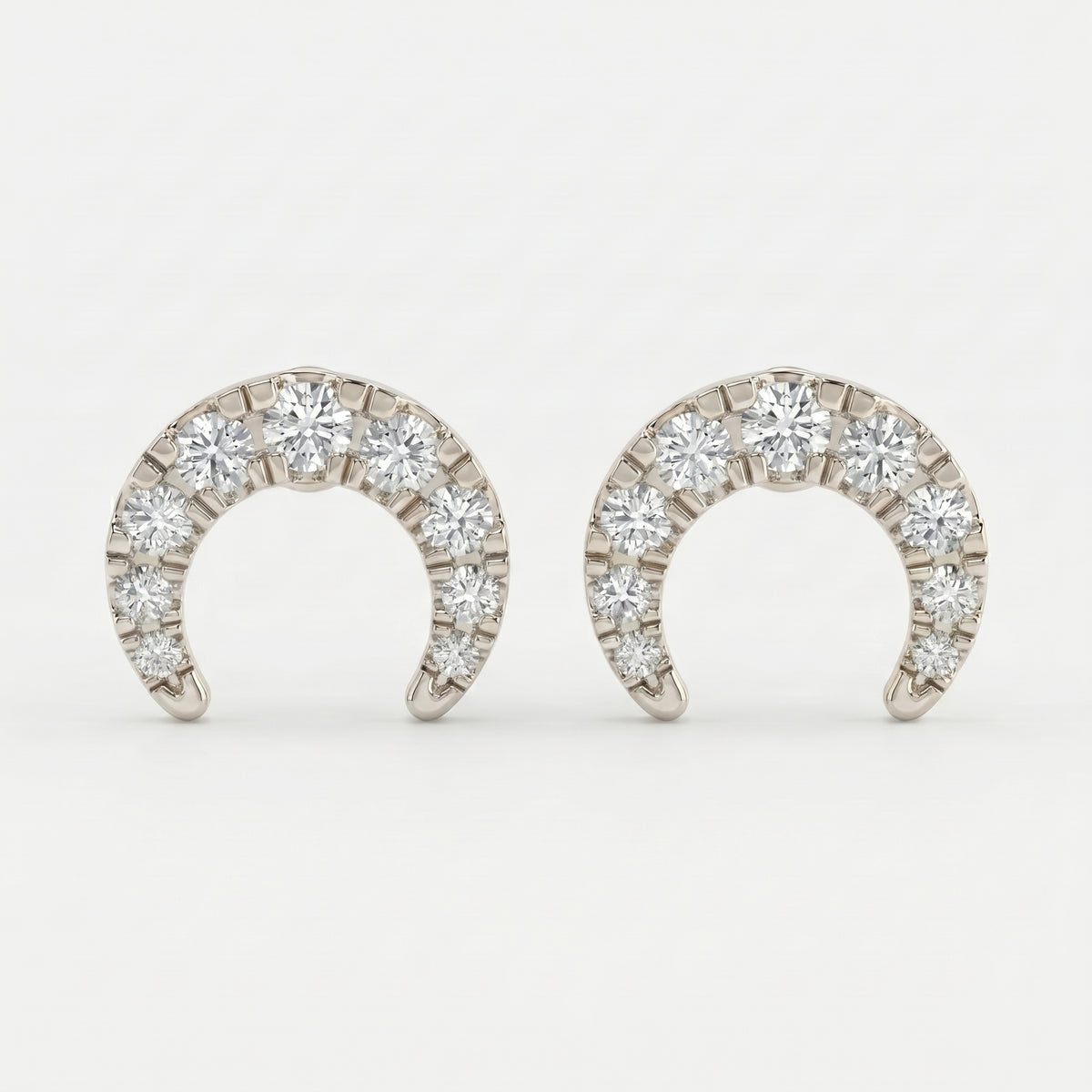 White gold pavé horseshoe stud earrings shown at 45-degree angle with brilliant diamond sparkle