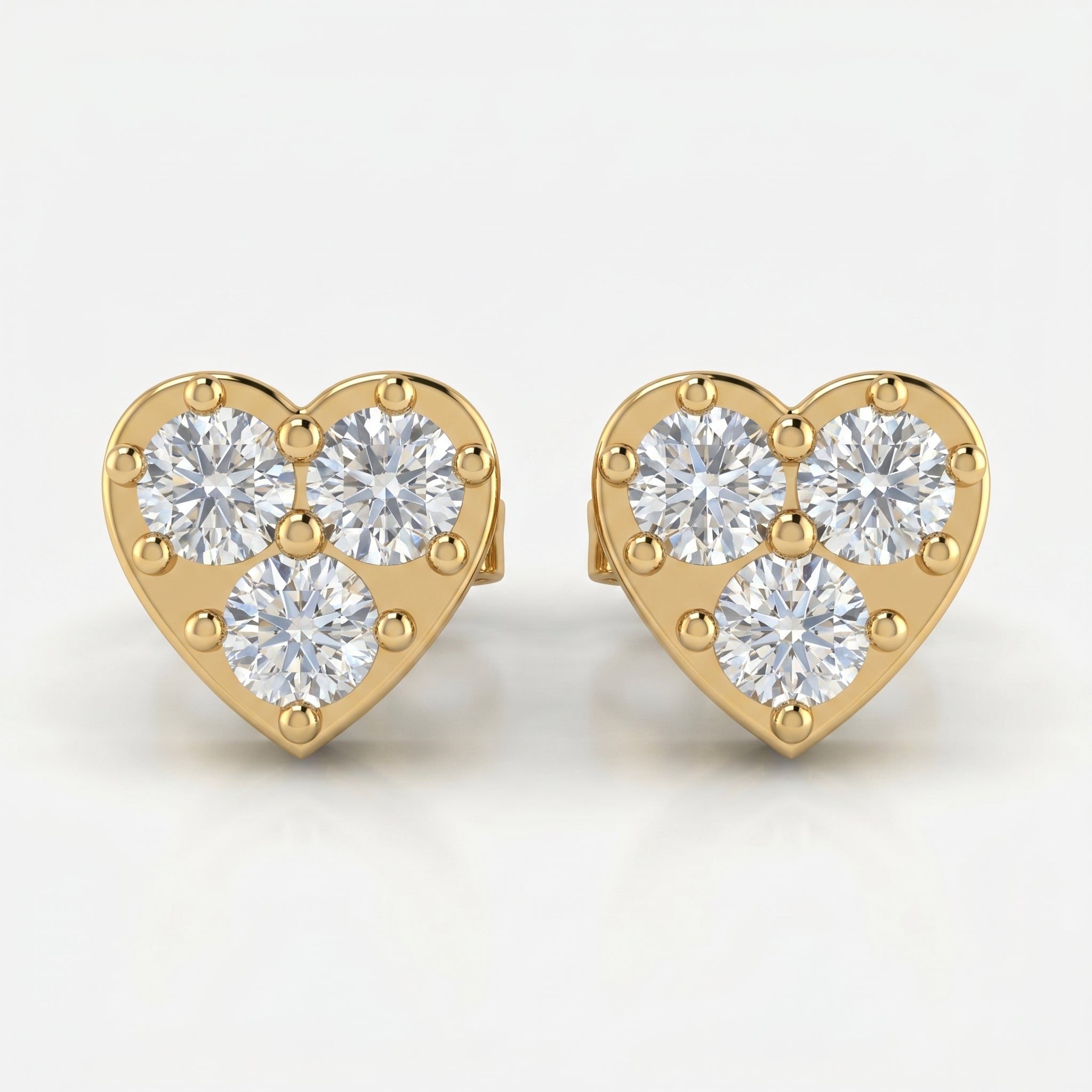 Heart-shaped yellow gold diamond stud earrings with three round brilliant diamonds on white background