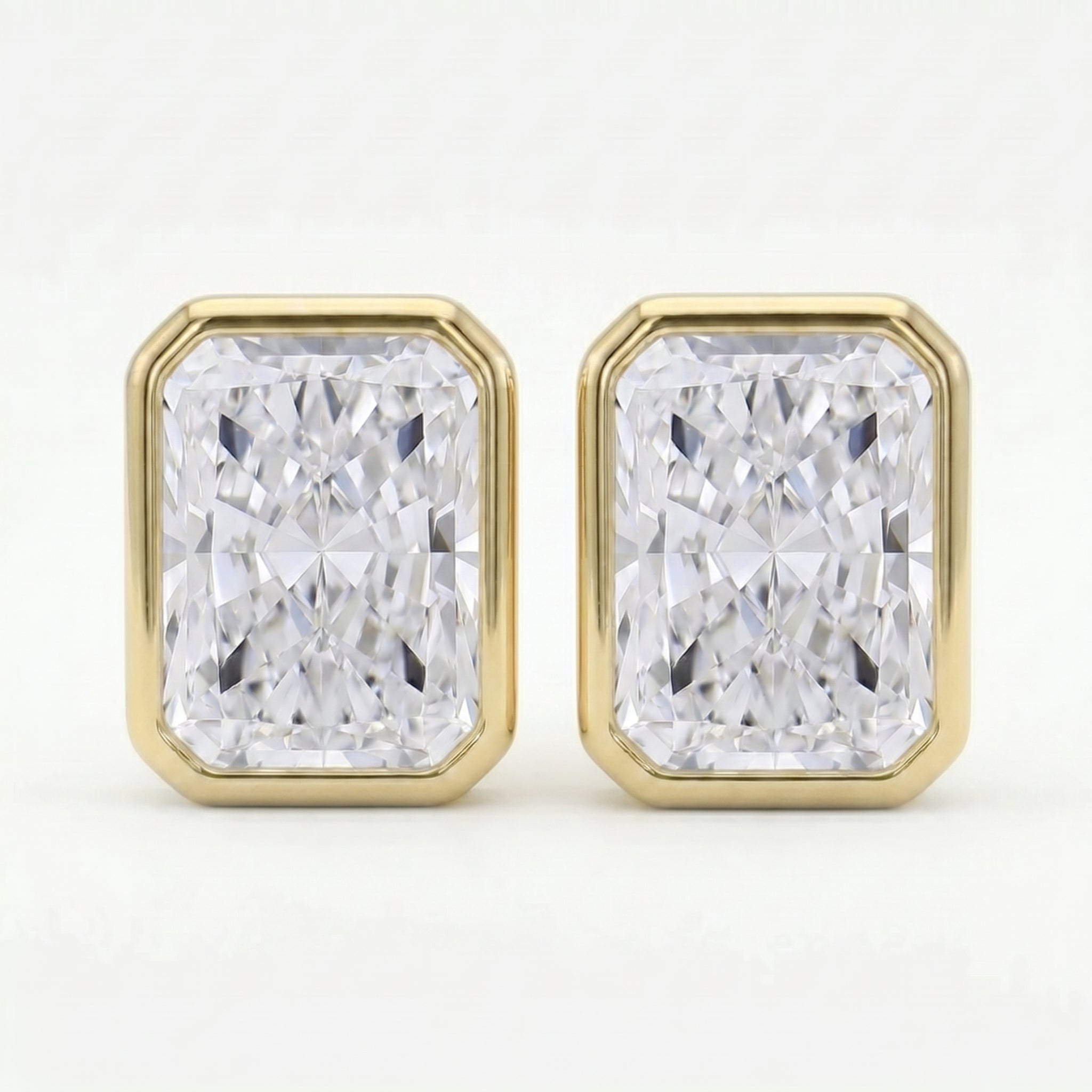 Gold earrings with rectangular diamond-like stones on a white background