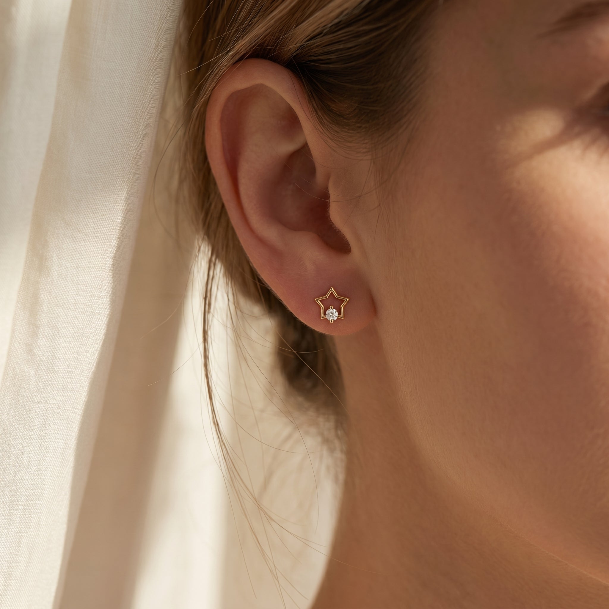 Macro close-up of crystal star earrings showing polished rose gold finish and sparkling solitaire gemstone detail