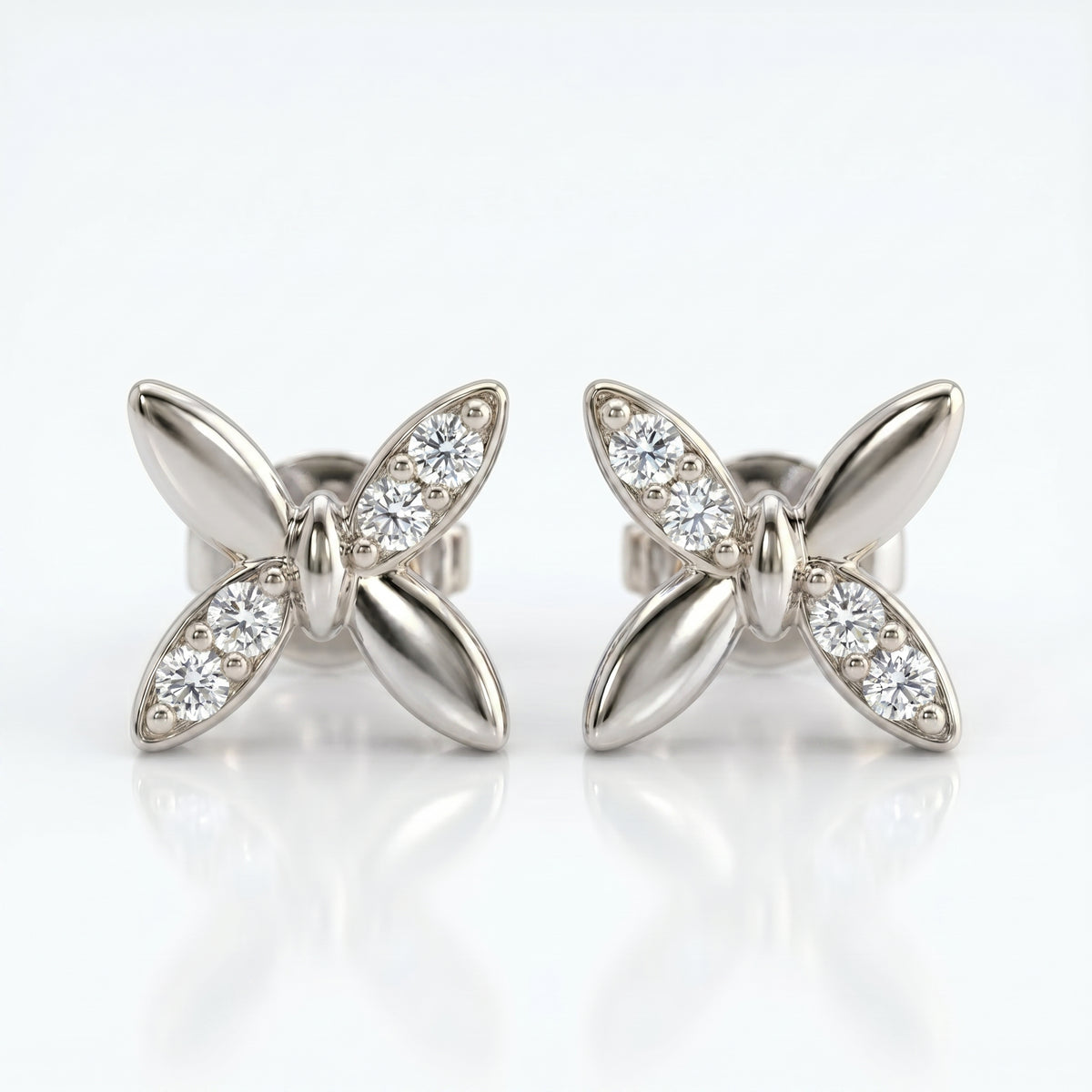White gold butterfly diamond stud earrings with pavé stones in a minimalist luxury jewelry studio setting