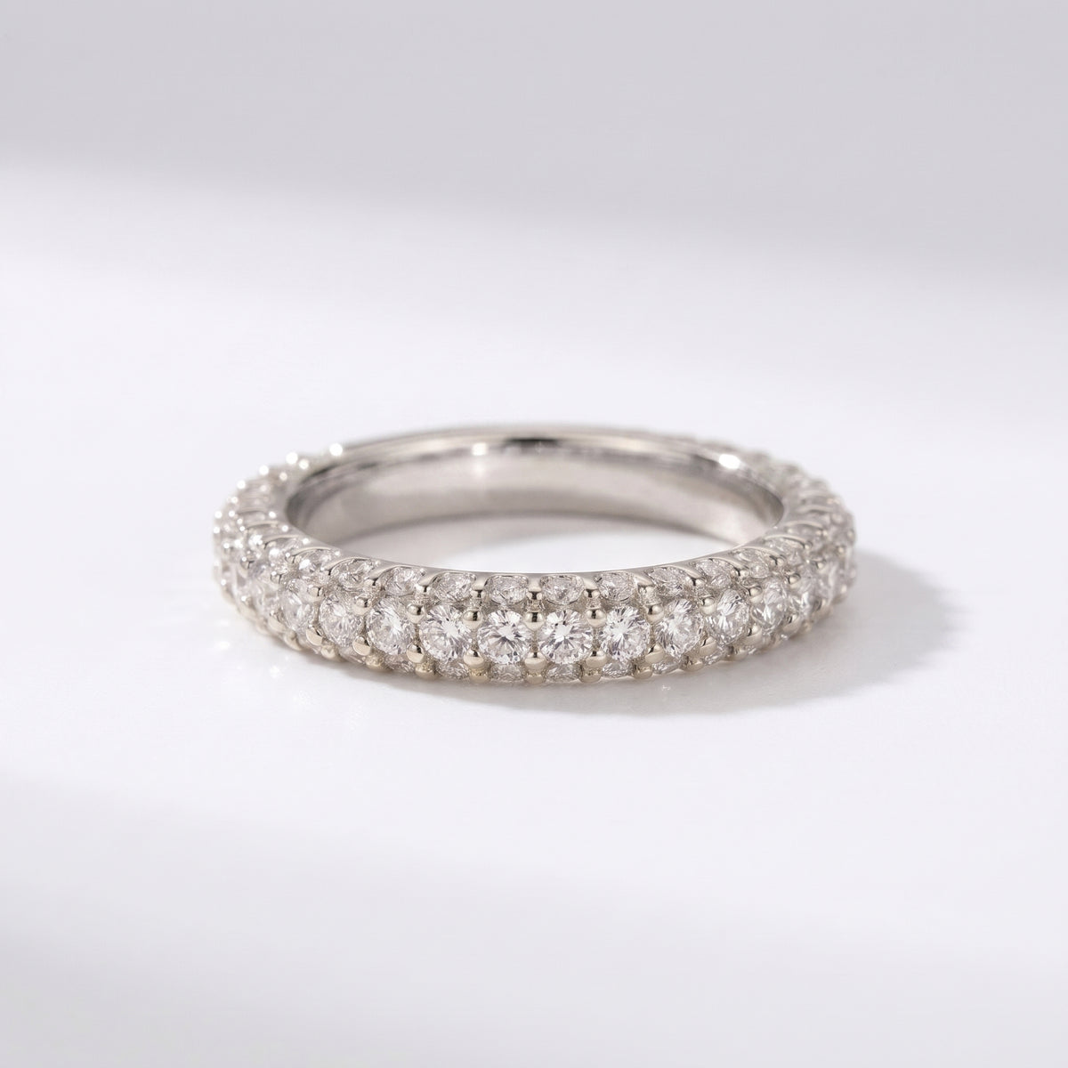 White gold diamond eternity band with round brilliant pavé diamonds, luxury wedding ring on a clean white background.