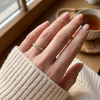 Round diamond eternity ring worn on a woman's finger, showcasing a delicate stackable wedding band in everyday luxury style.