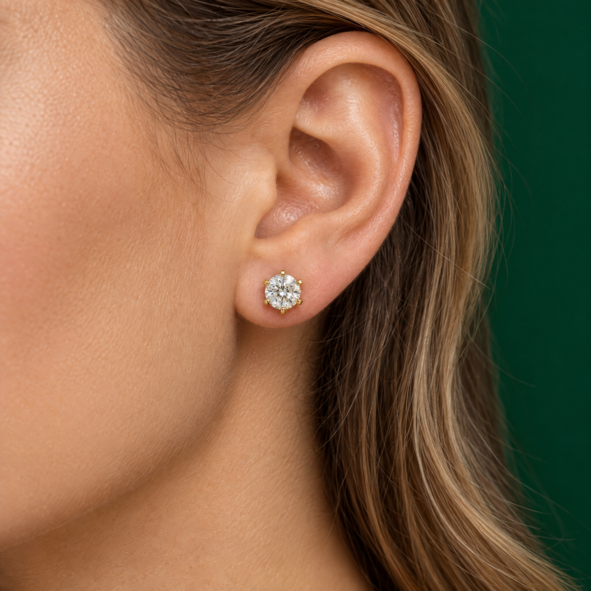 Round diamond stud earring in 18K yellow gold worn on the ear