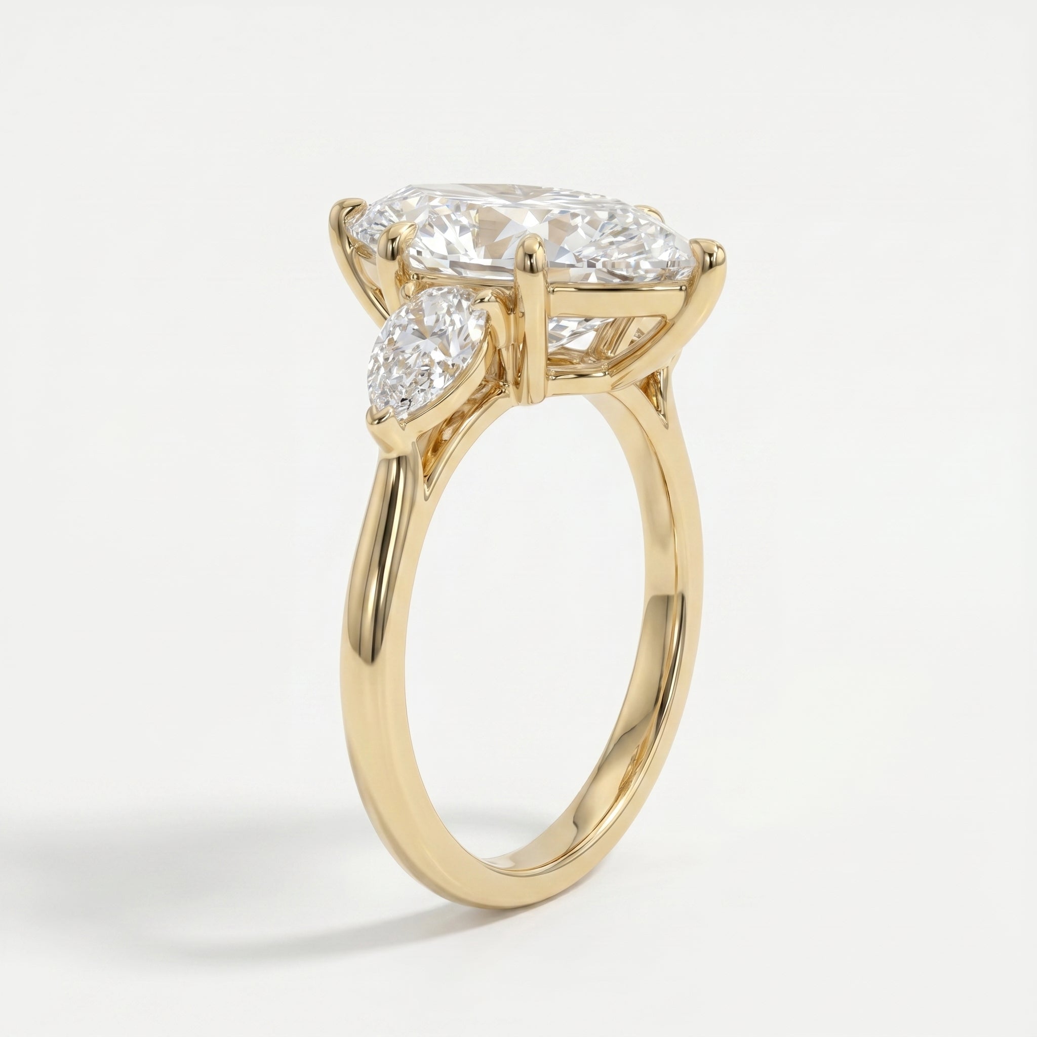 Yellow gold marquise diamond engagement ring with pear side stones shown at a 45 degree luxury studio angle
