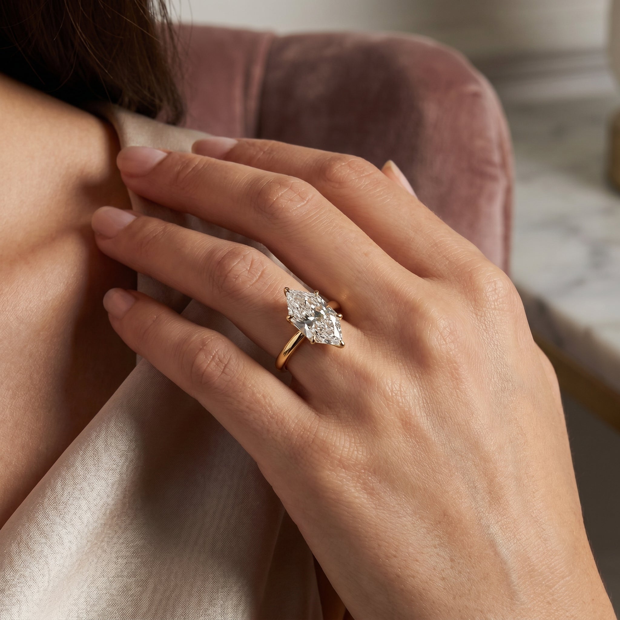 Marquise cut diamond engagement ring in yellow gold solitaire setting worn on hand with brilliant sparkle