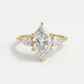 Marquise diamond three stone engagement ring in yellow gold with pear side diamonds on a clean white background