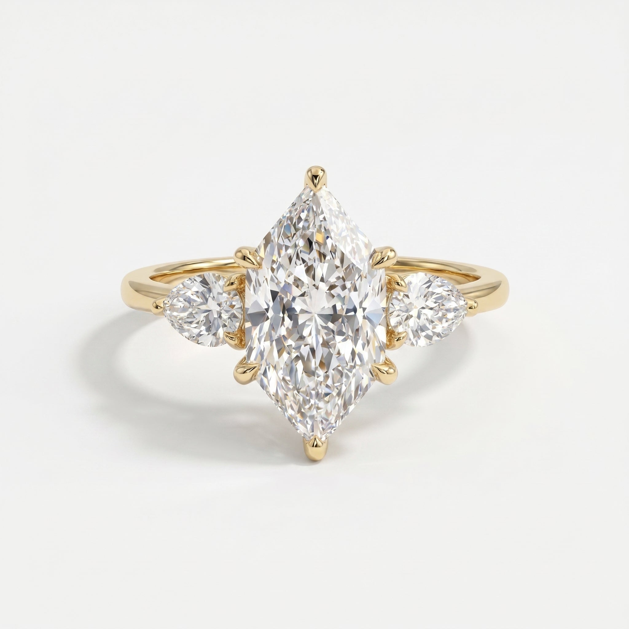 Marquise diamond three stone engagement ring in yellow gold with pear side diamonds on a clean white background