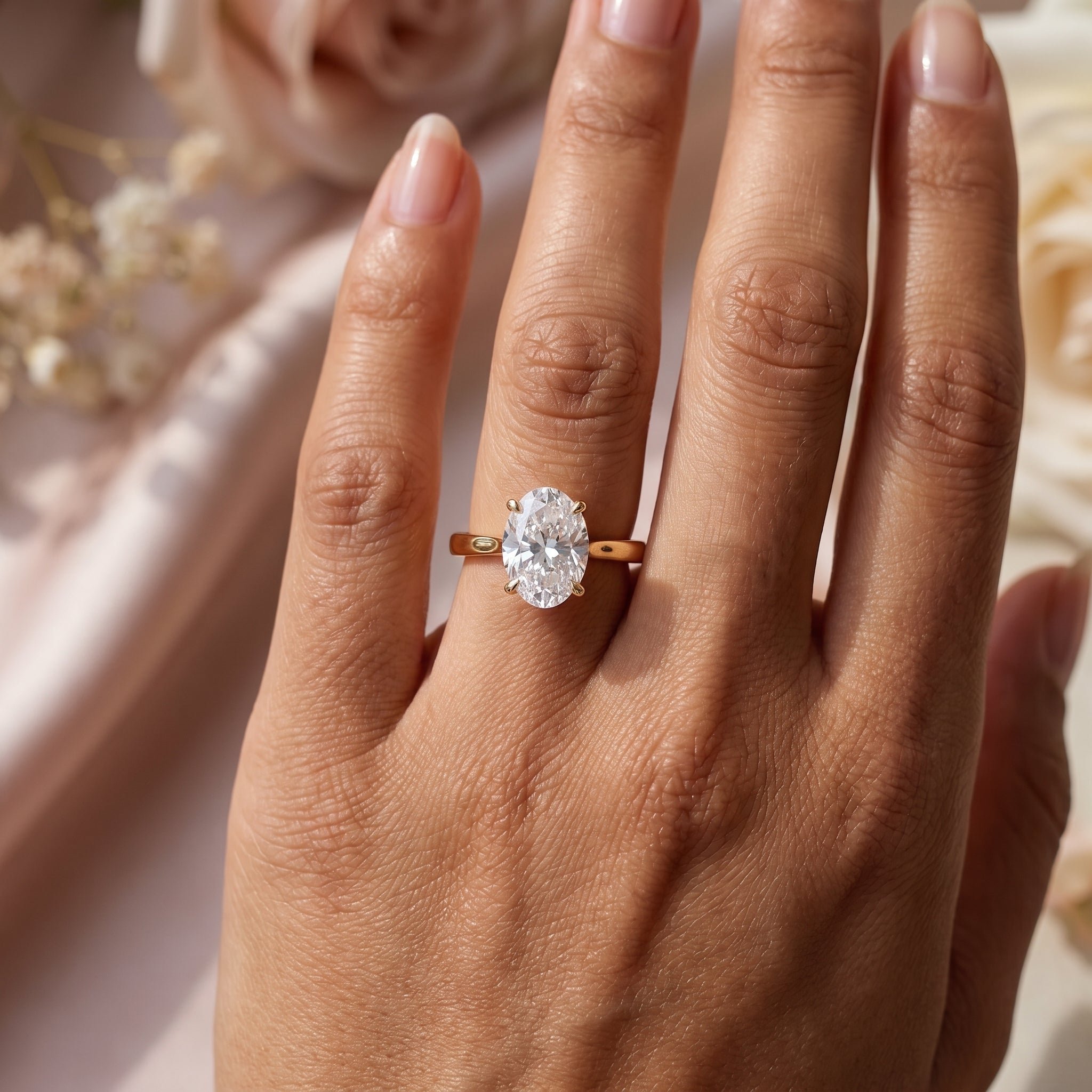 Oval solitaire diamond engagement ring worn on hand showcasing the polished yellow gold band and elegant minimalist design.