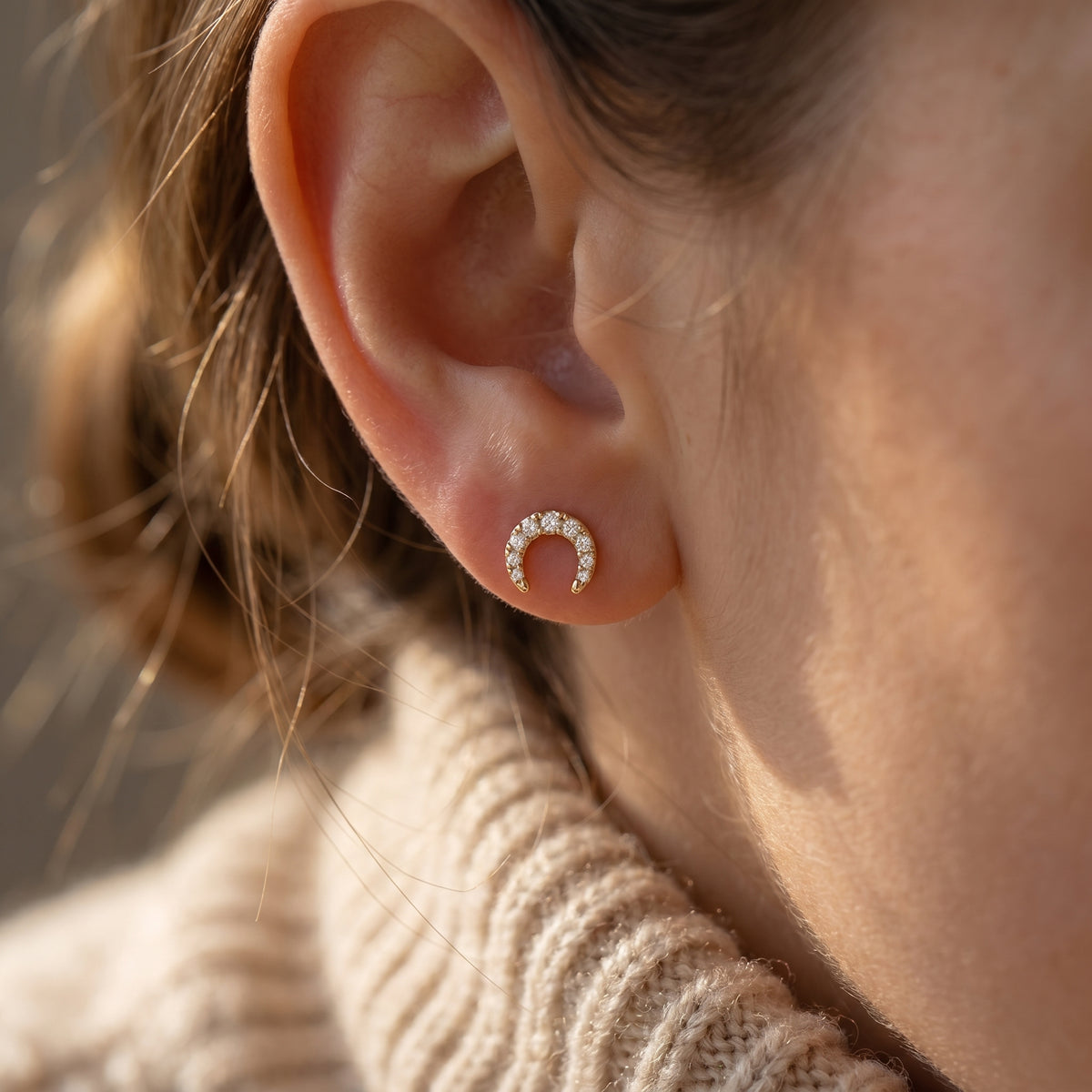 Side profile of pavé diamond horseshoe earrings showing fine gold setting and craftsmanship details