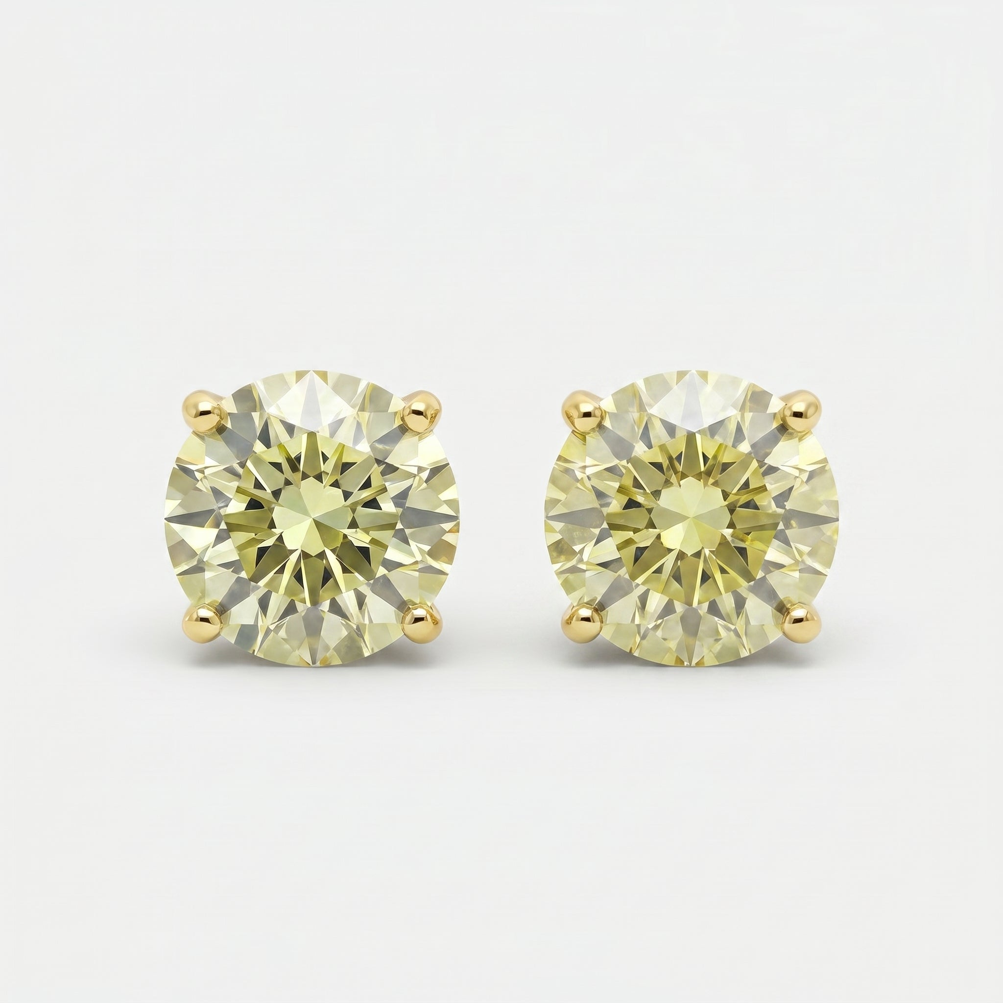 Round yellow diamond stud earrings in yellow gold setting on white background with brilliant sparkle and luxury finish