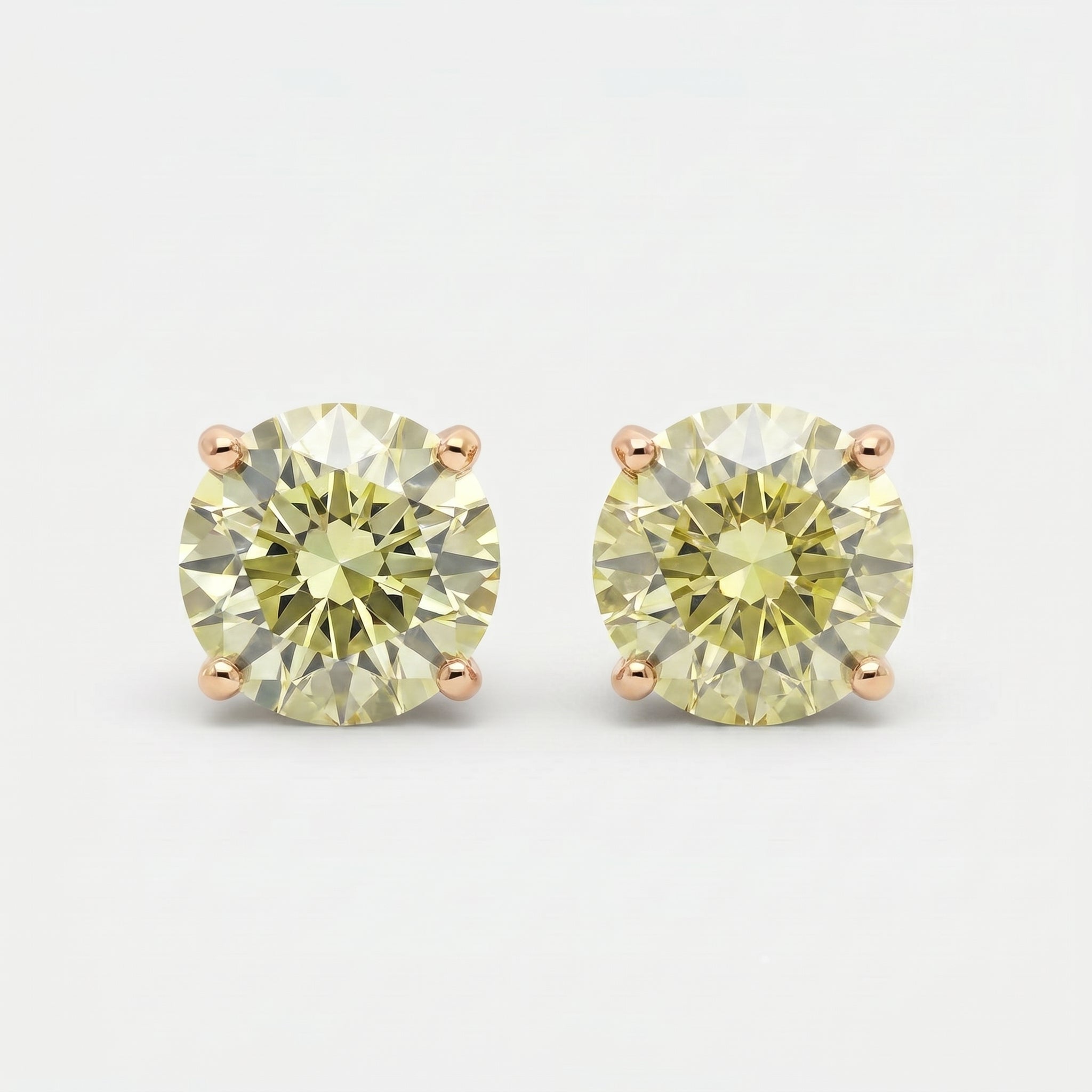 Round yellow diamond stud earrings with four-prong setting on white background in luxury minimalist style