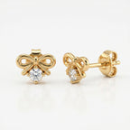 Woman wearing minimalist yellow gold bow earrings with sparkling crystal in elegant everyday styling