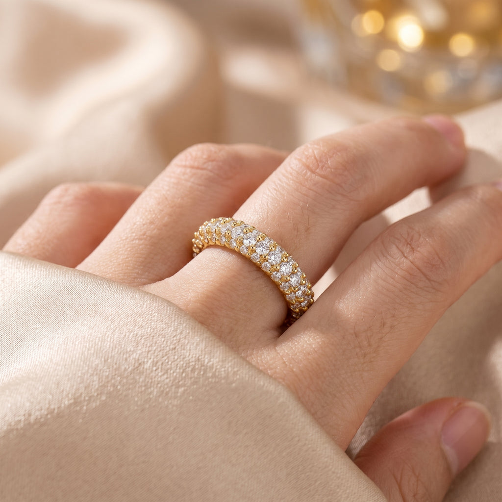 Woman wearing a yellow gold diamond eternity band with triple-row pavé diamonds in natural lifestyle lighting.